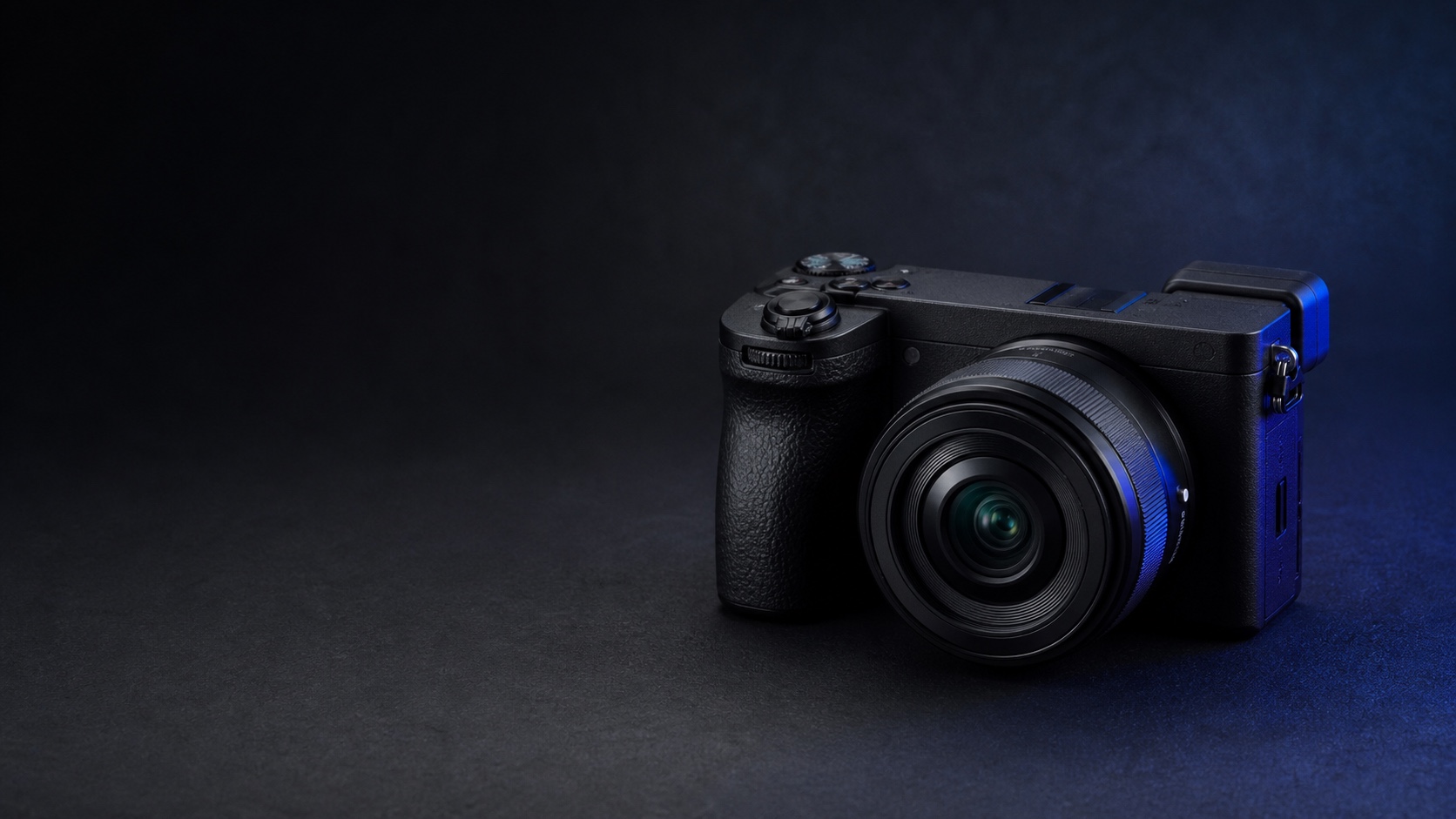 Фотореалистичная предметная иллюстрация Sony Alpha 6700 с компактным объективом в тёмной графитовой студии с синим акцентом. Иллюстрация для страницы «Продать Sony Alpha 6700 в Москве дорого сегодня».